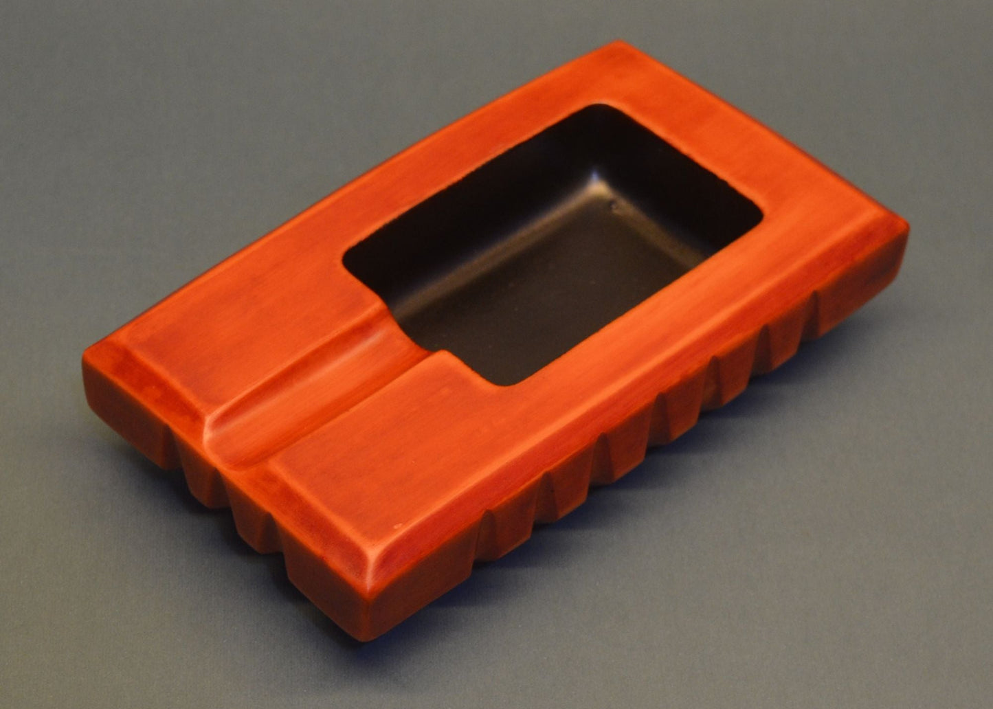 Orange rectangular ashtray with a central cutout on a gray background