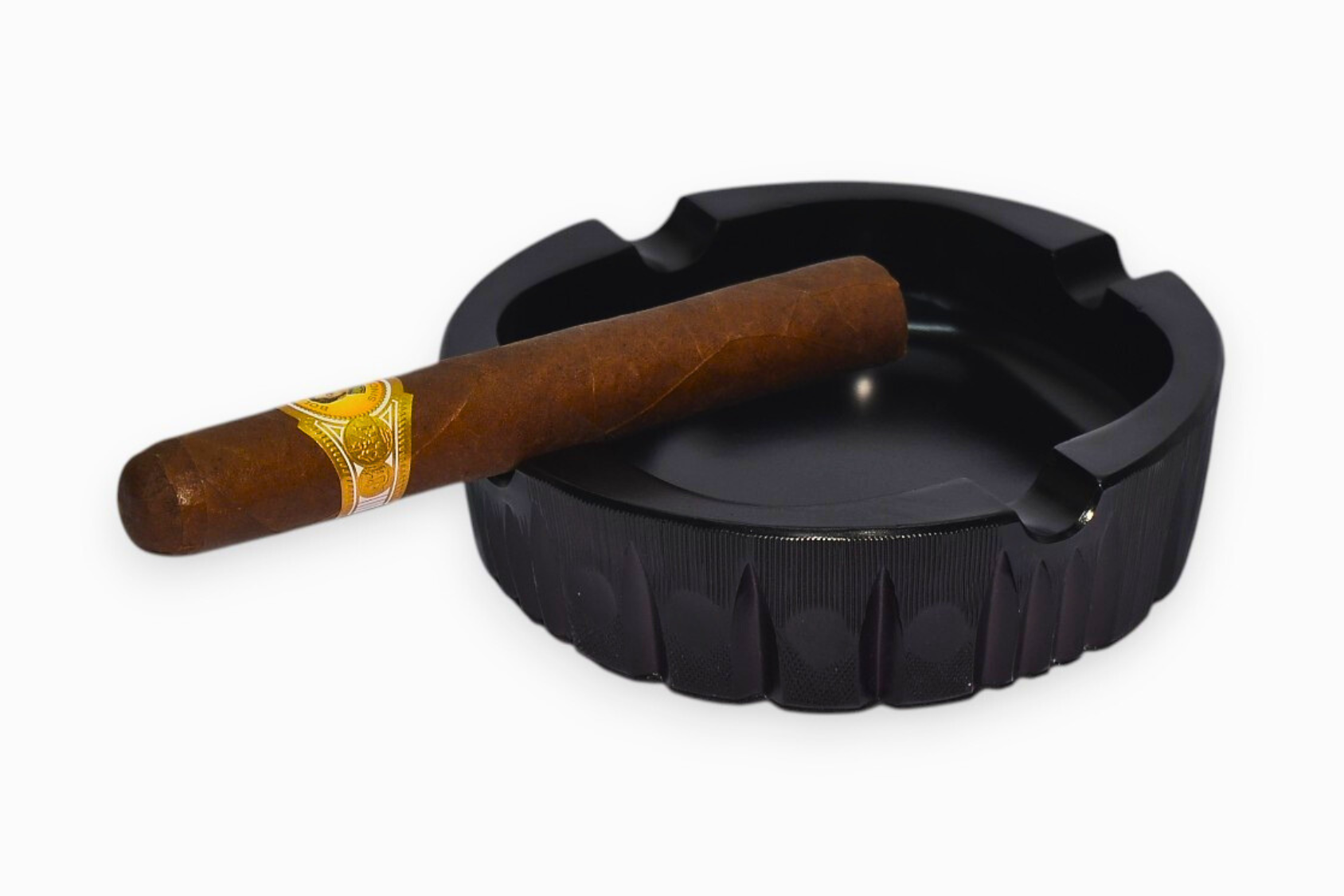 Black ashtray with a wooden cigar on a white background