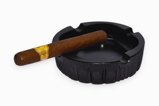 Black ashtray with a wooden cigar on a white background