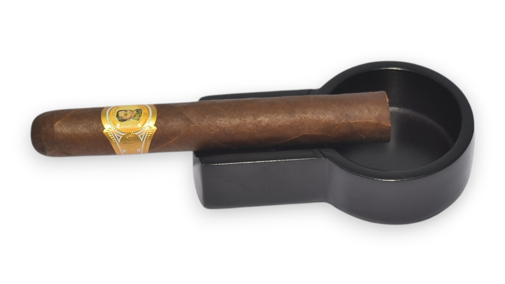 Cigar with a band resting on a black ashtray against a white background