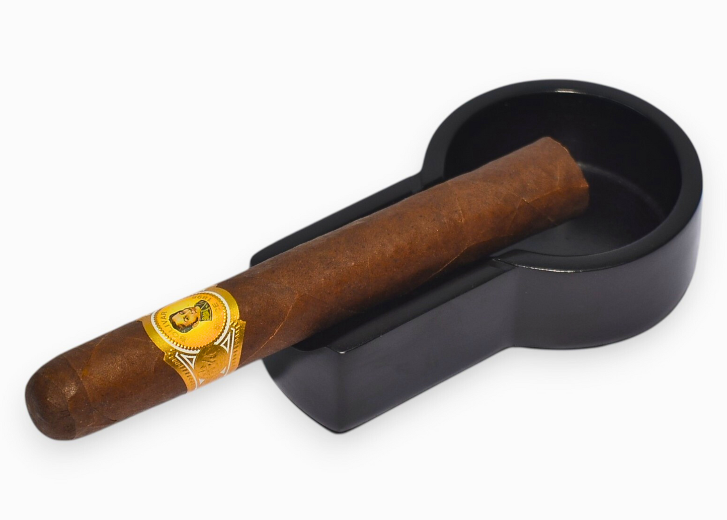 Cigar with a label in a black ashtray on a white background