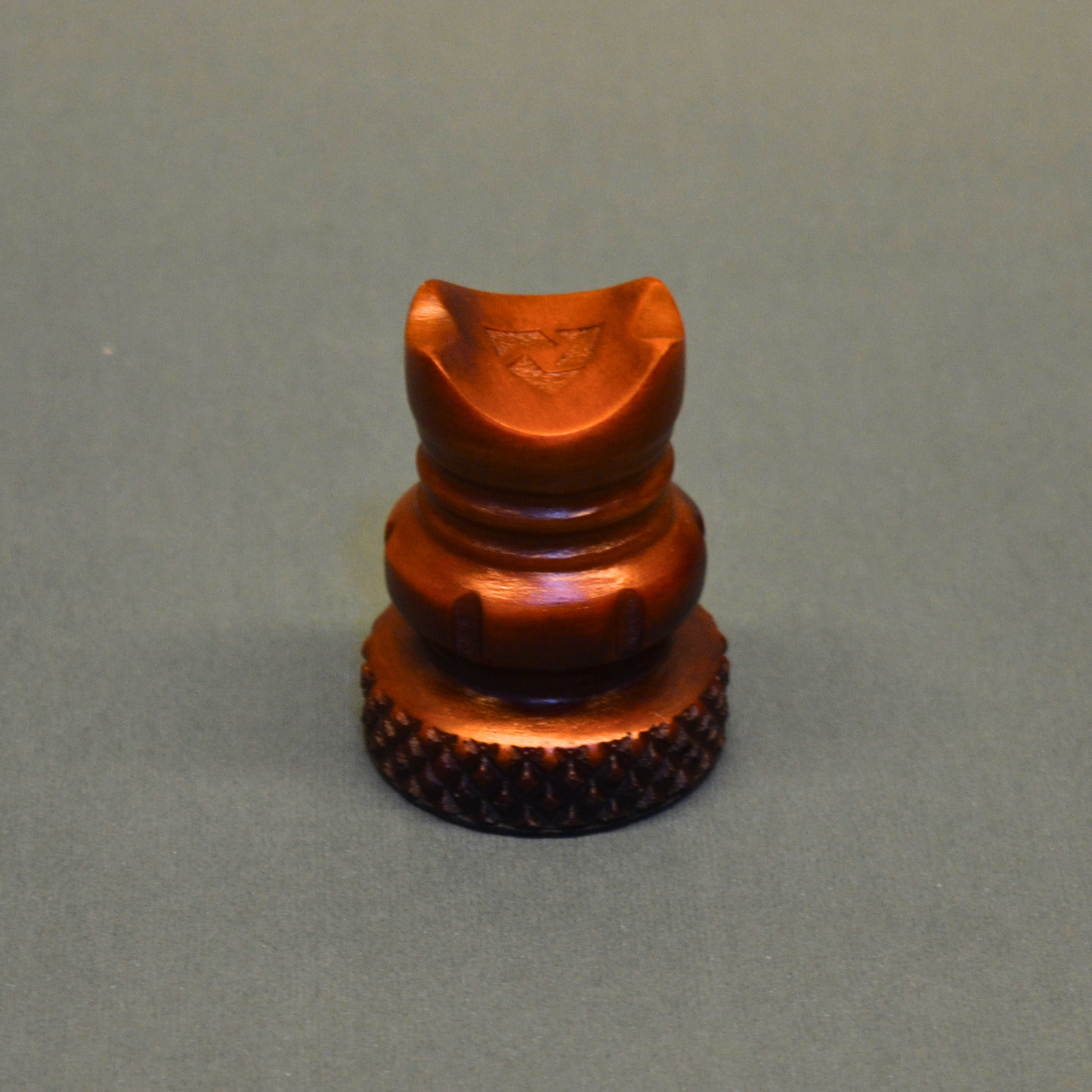 Bronze-colored metal object on a gray background