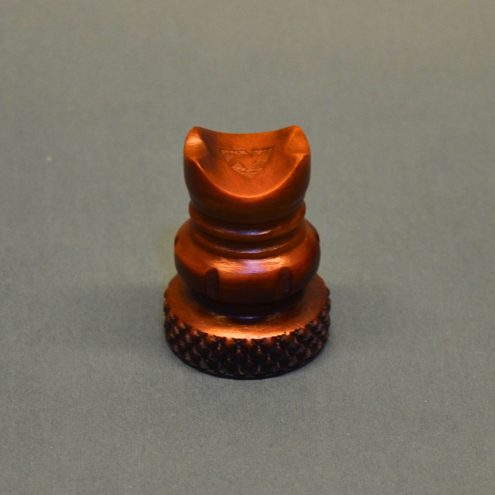 Bronze-colored metal object on a gray background