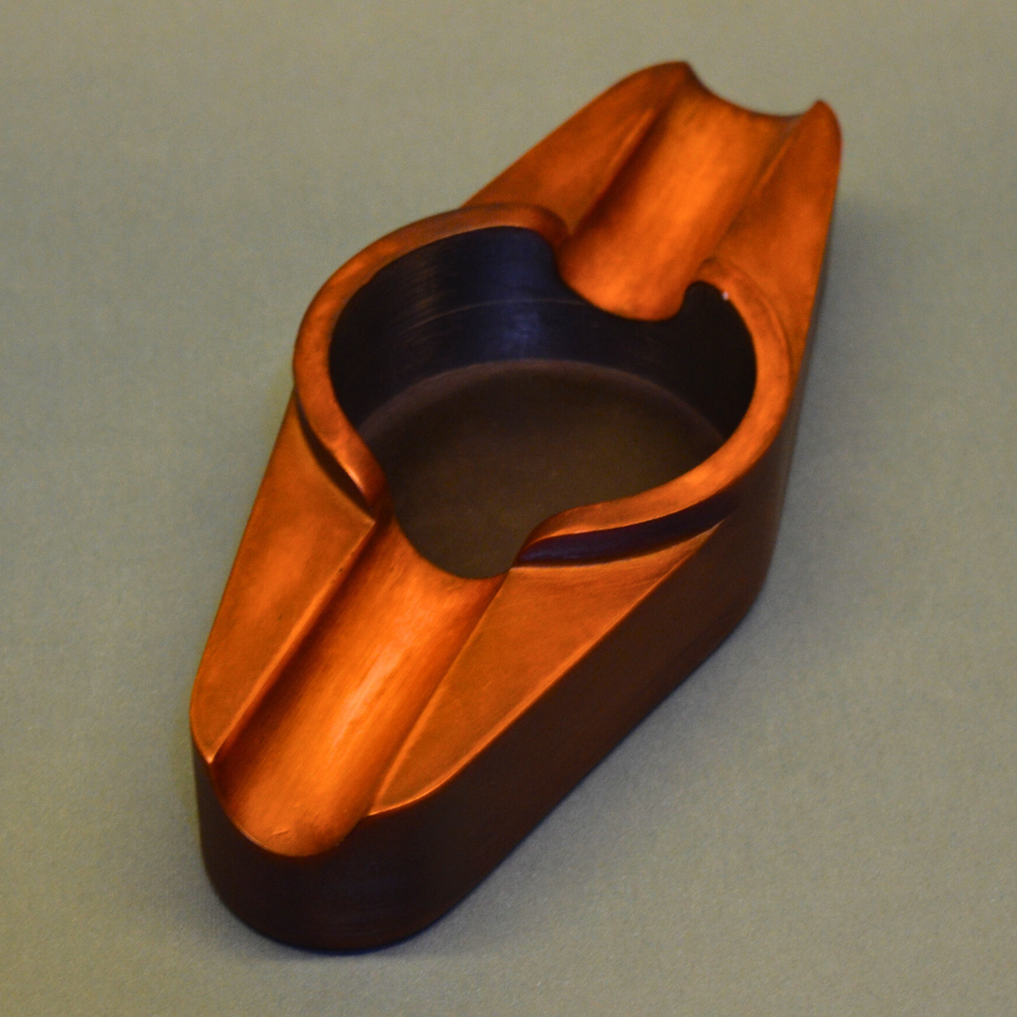 A cigar ashtray with two cigar rests and a round ash hole (brown)