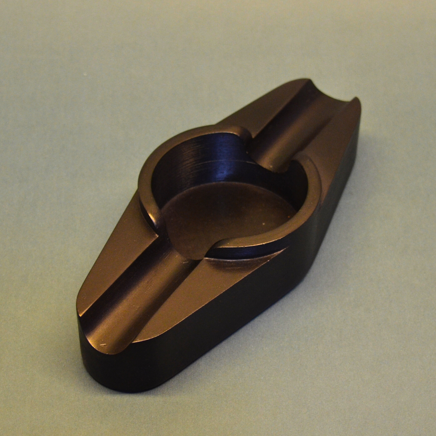 A cigar ashtray with two cigar rests and a round ash hole (black)