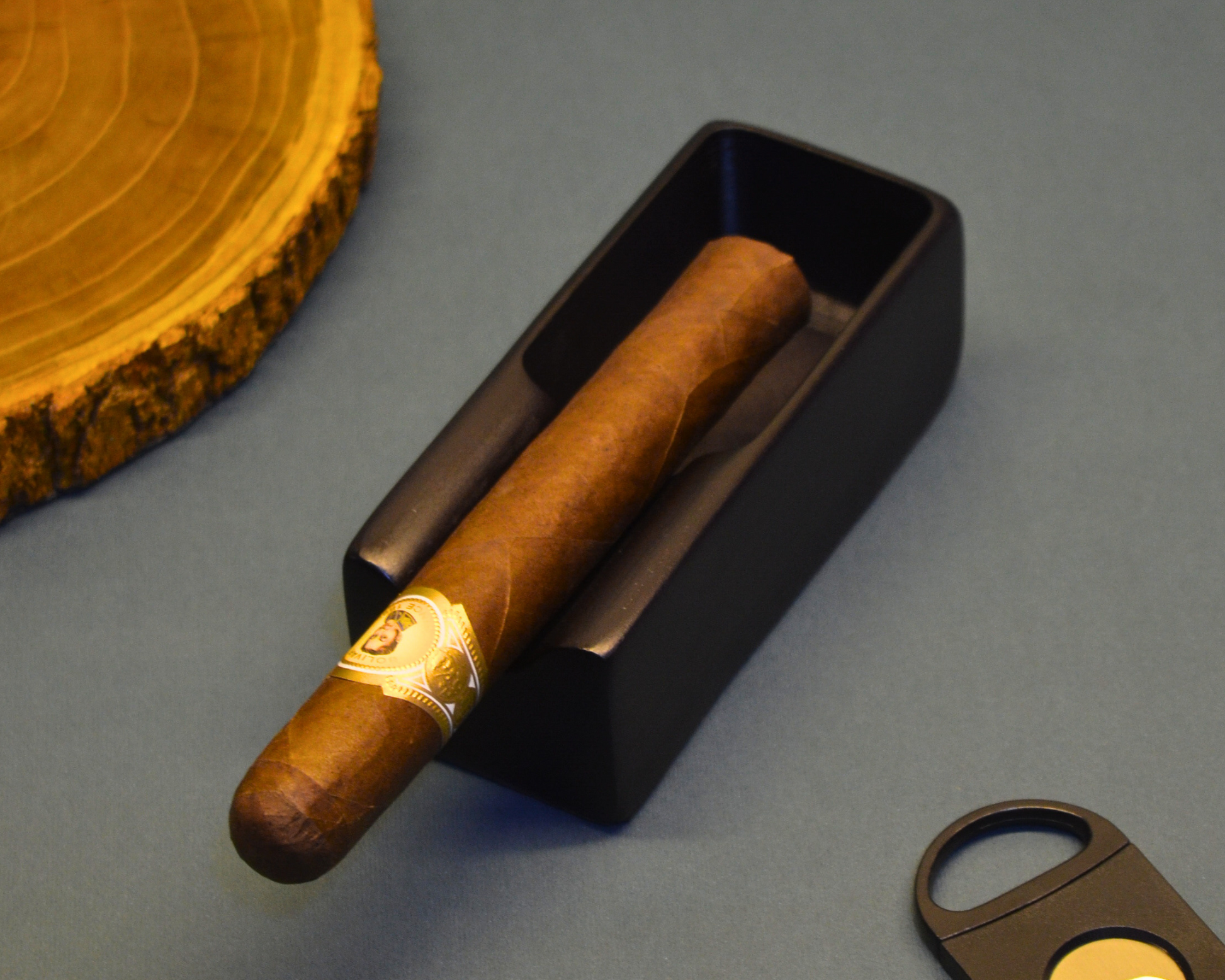 Cigar with gold band in a black humidor on a gray surface