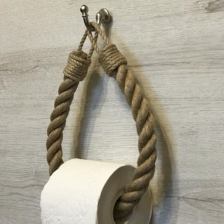 Rustic paper towel holder made of rope and metal on a wooden wall.