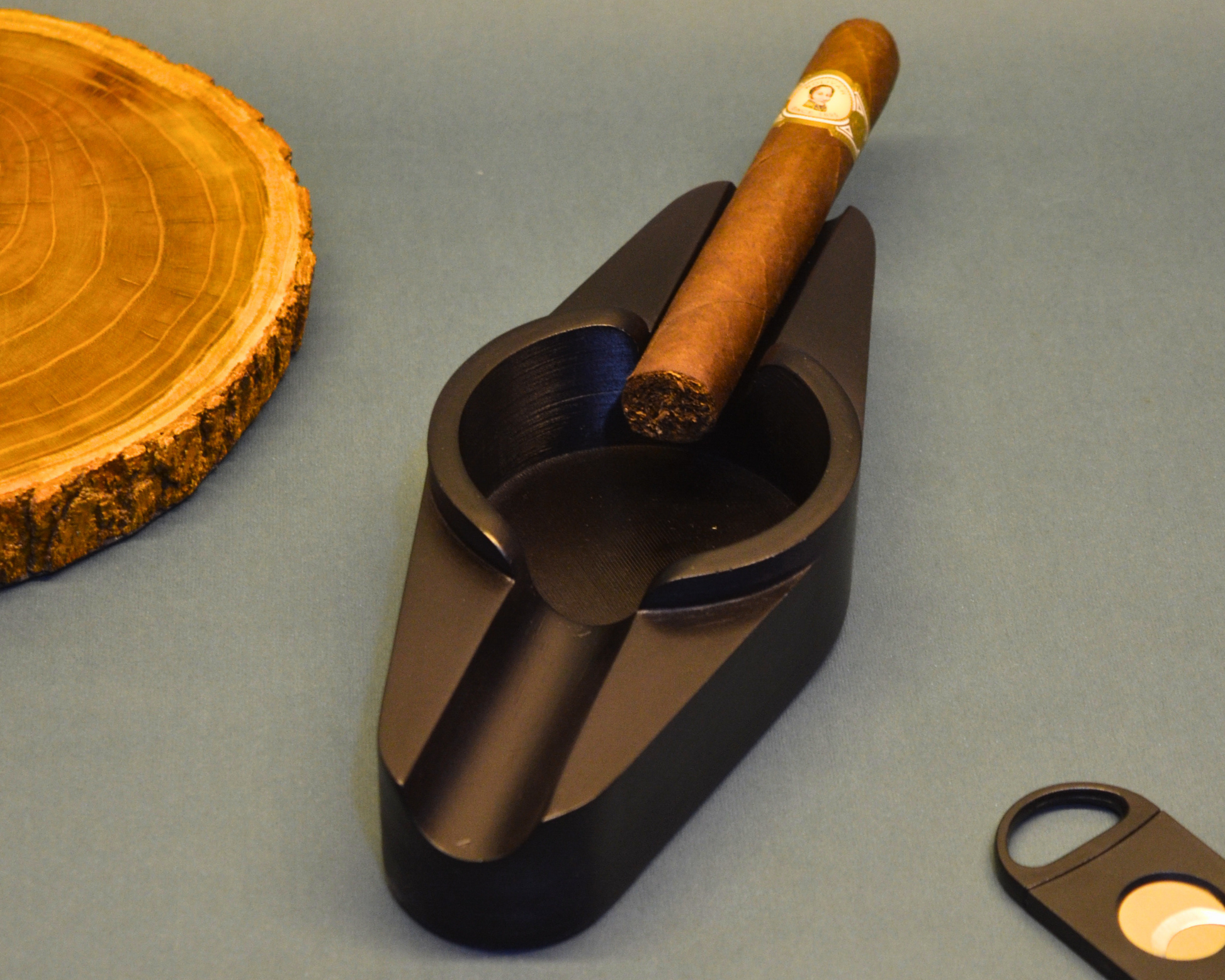 Cigar in a black holder with a wooden slice and cutter on a gray background
