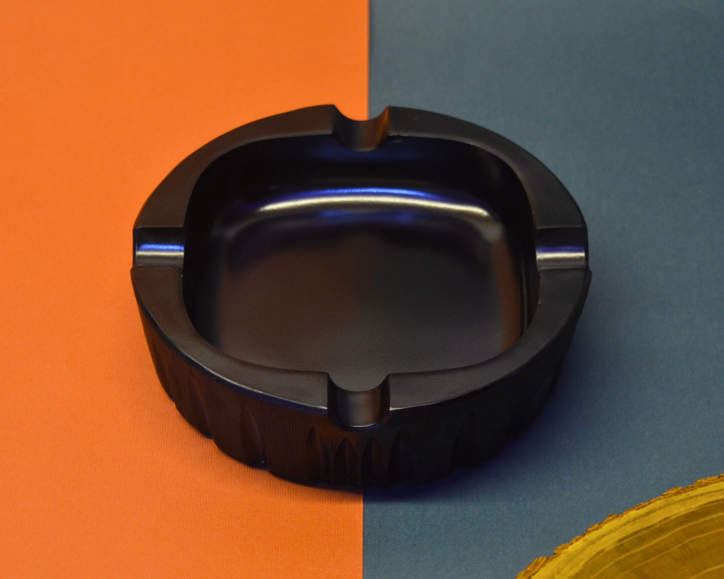 Black ashtray on a split orange and blue background
