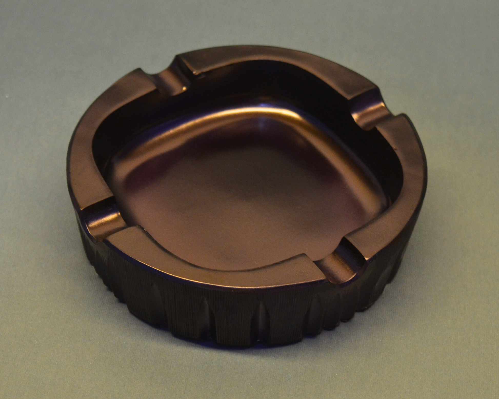 Bronze-colored metal ashtray on a gray background