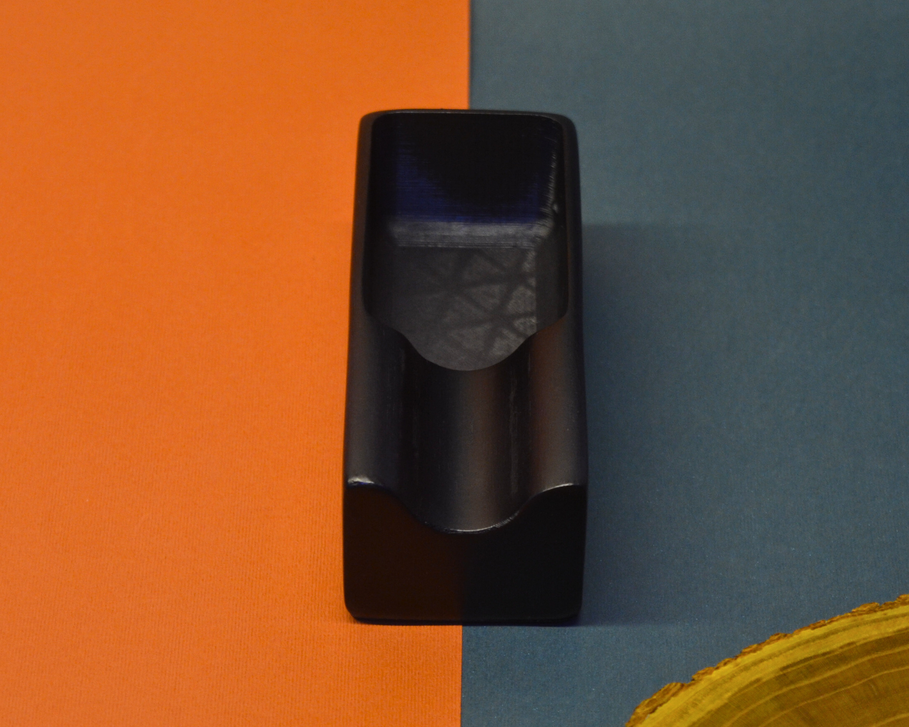 Black ashtray object on a split orange and blue background