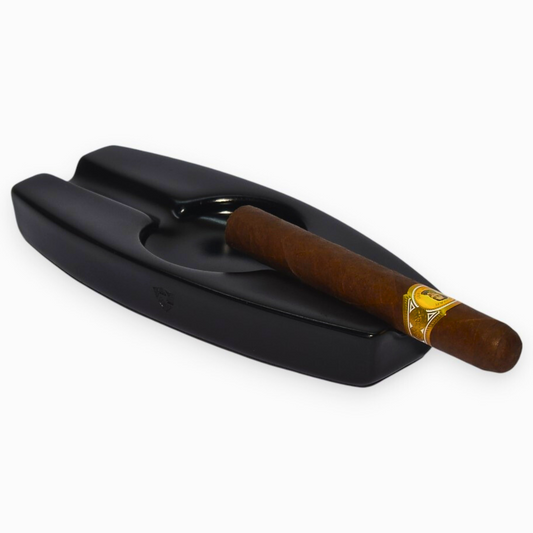 Black cigar ashtray with a single cigar on a white background
