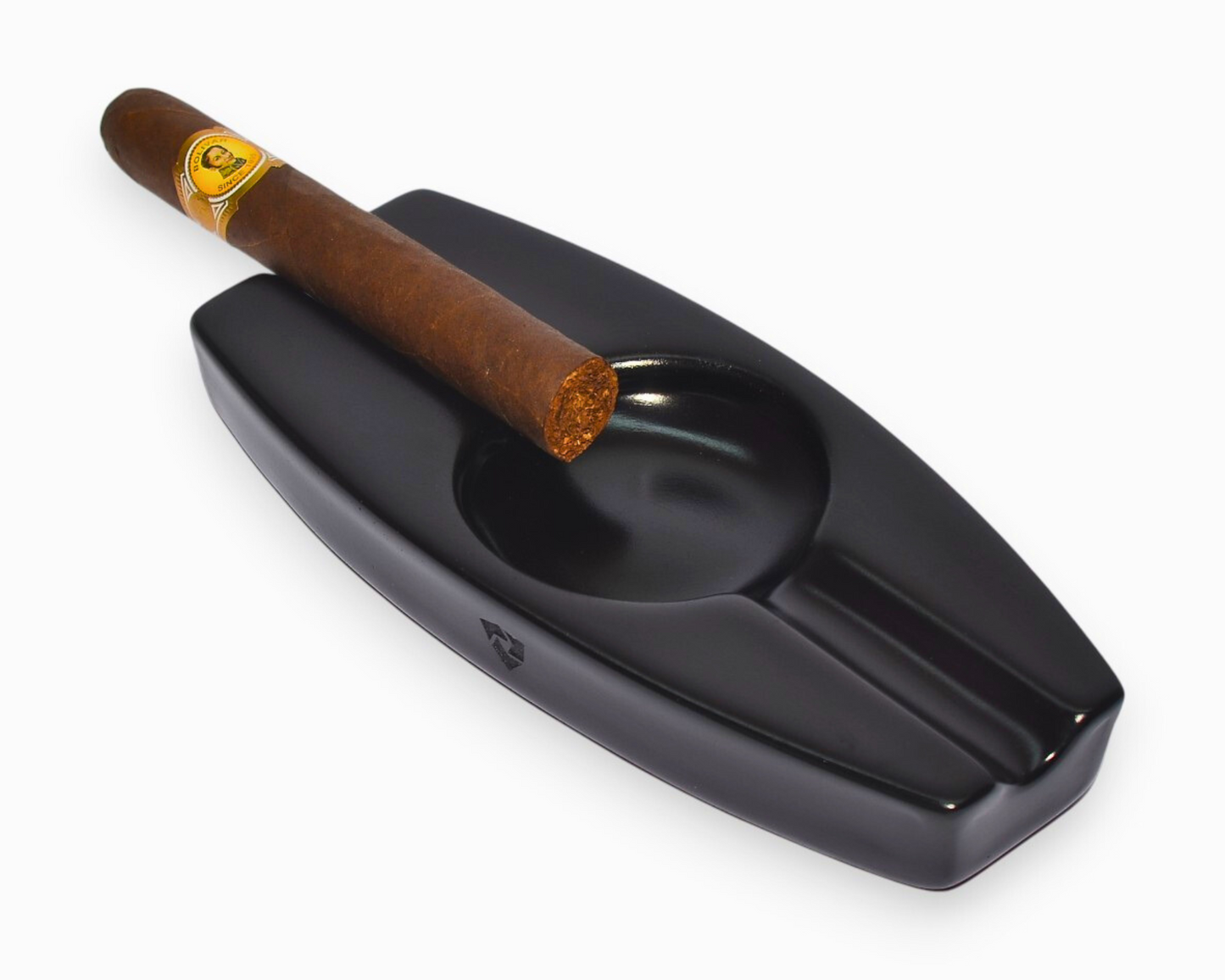 Black ceramic cigar ashtray with a single cigar on a white background