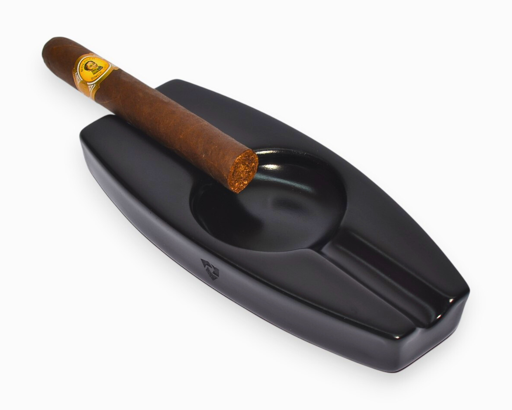 Black ceramic cigar ashtray with a single cigar on a white background