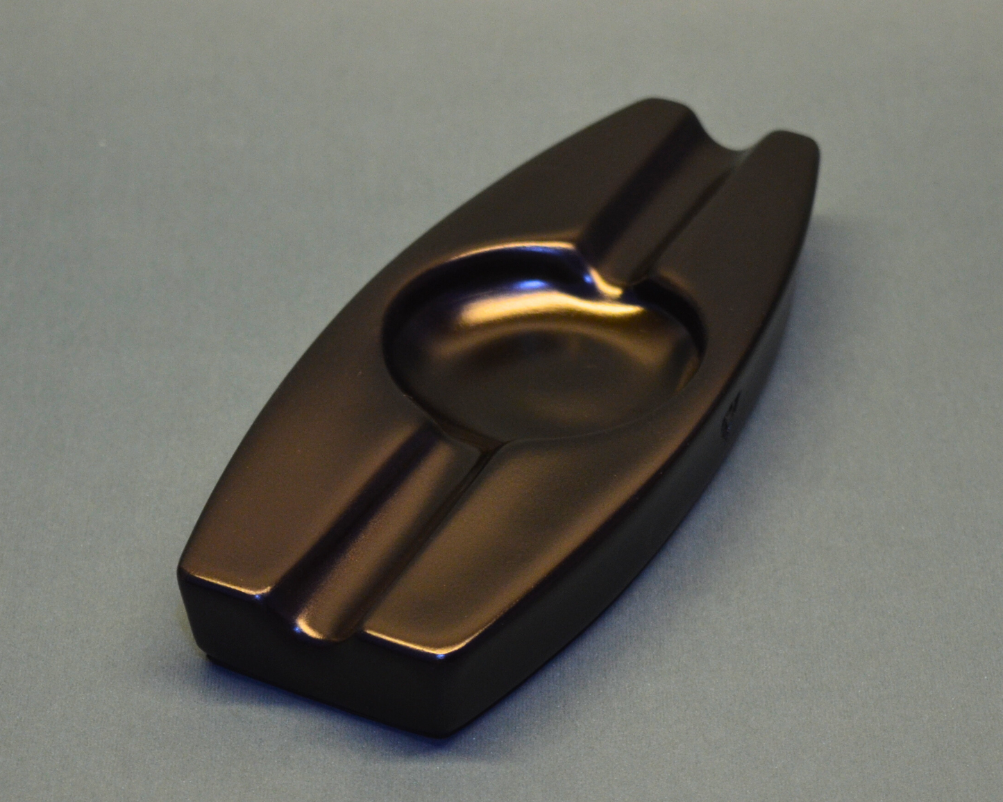 Bronze-colored metal ashtray on a gray background