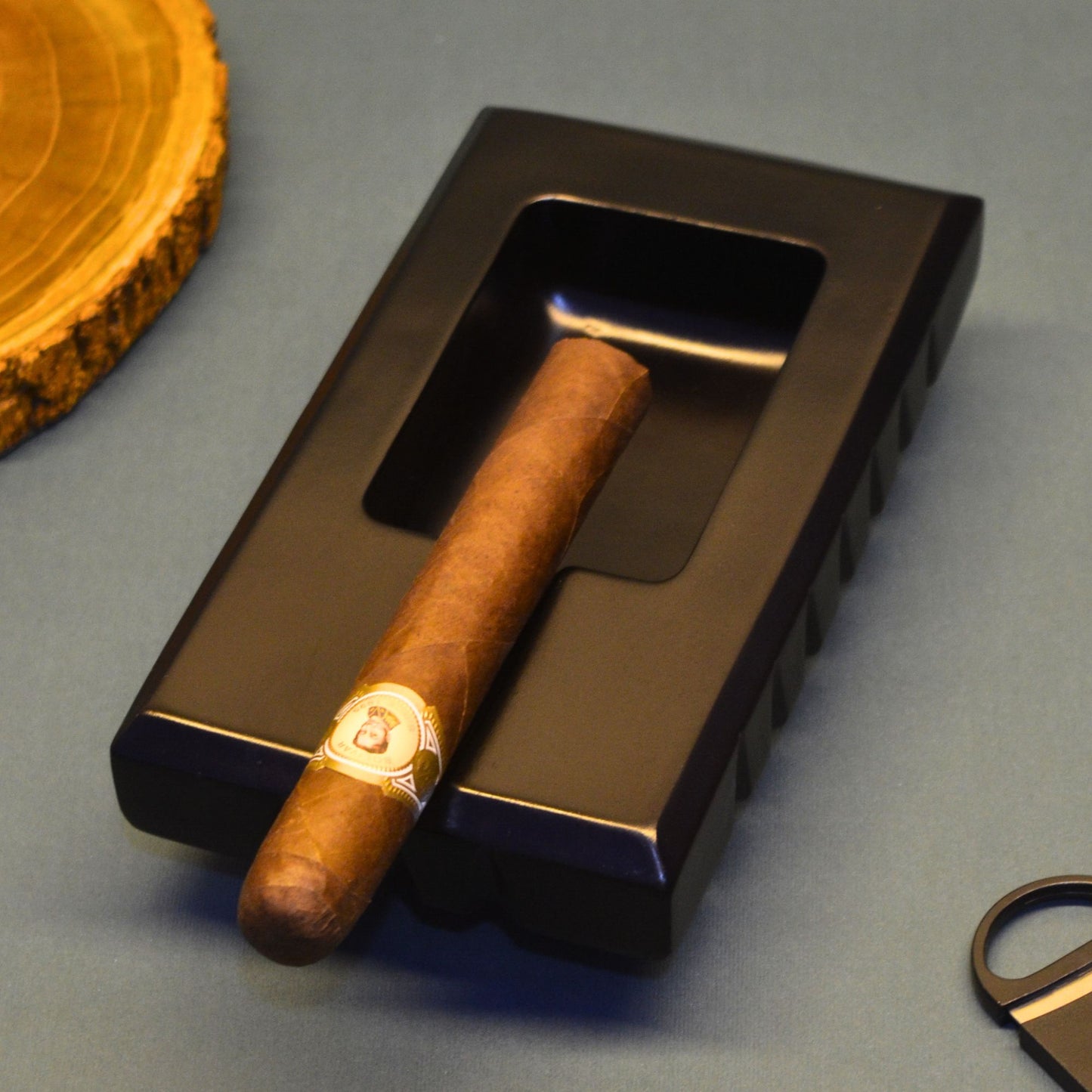 Cigar ashtray on a black metal tray with a wooden coaster in the background