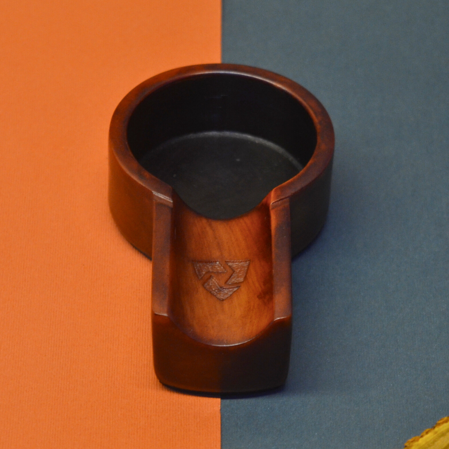 Wooden cup holder with black interior on an orange and blue background