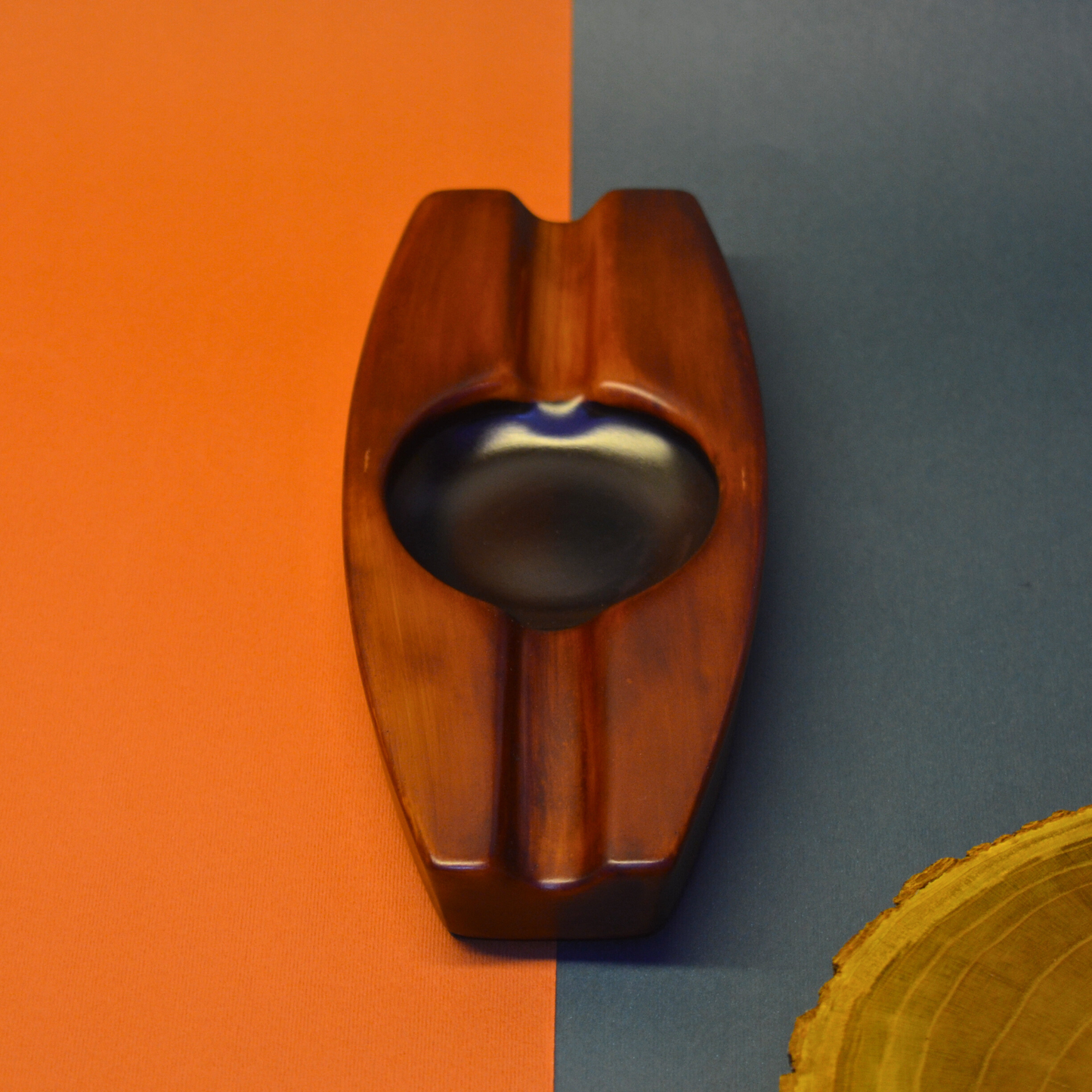Wooden ashtray on a two-tone orange and blue background