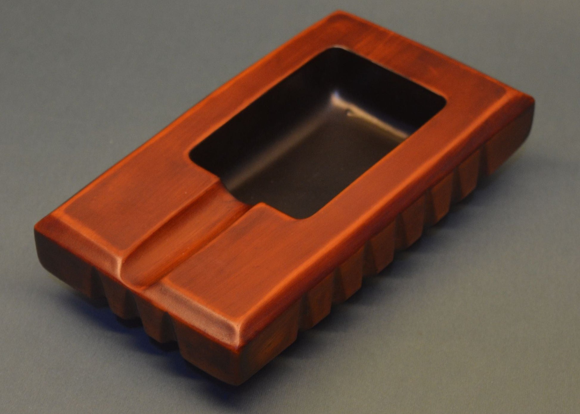 Rectangular brown ashtray with a central cutout on a gray background