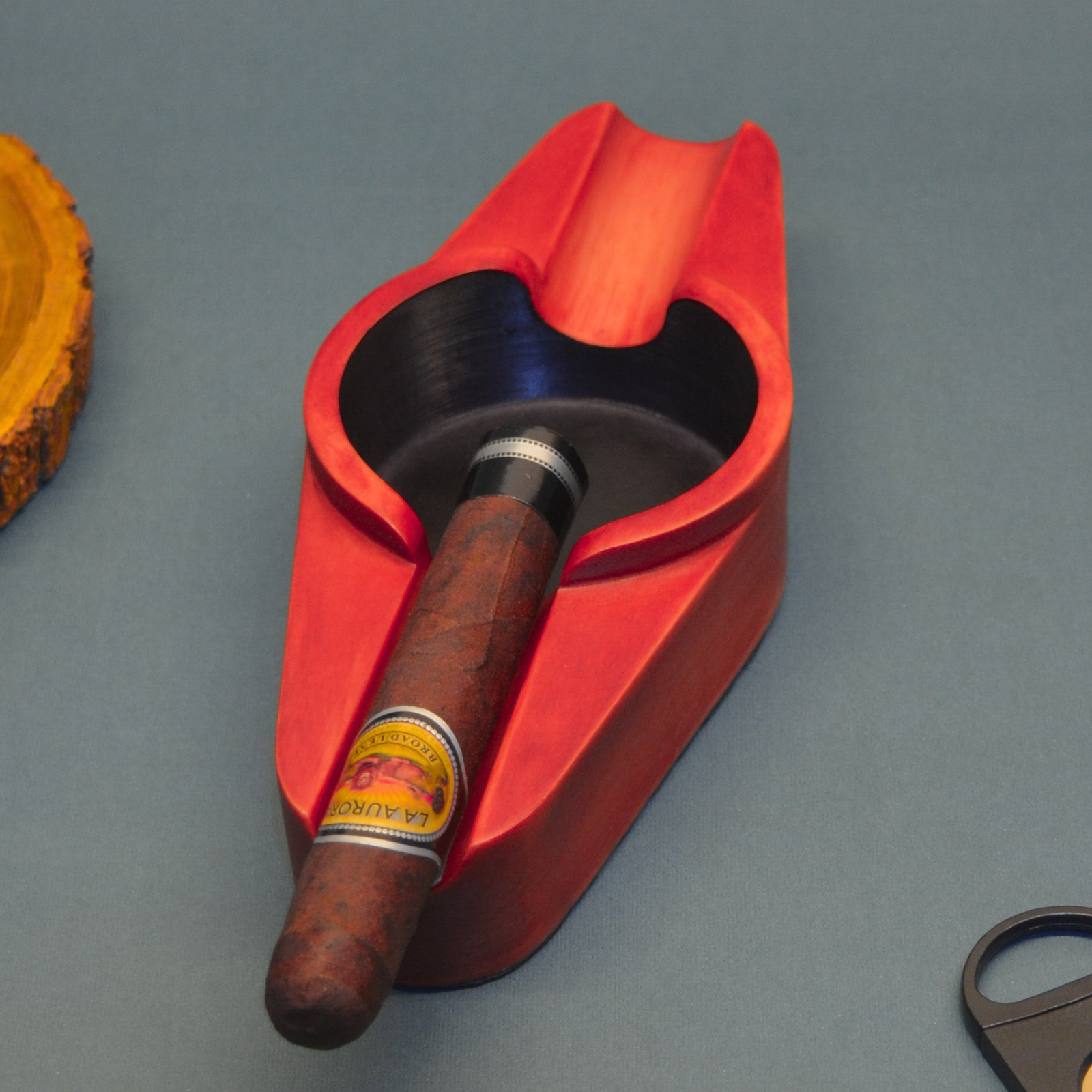 Red cigar holder with a cigar and cutter on a gray background