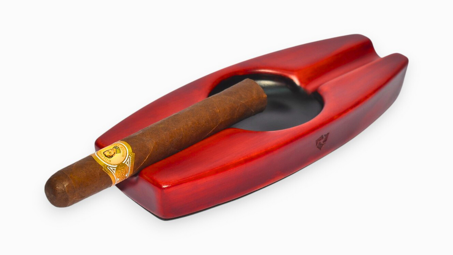 Red cigar ashtray with a single cigar on a white background
