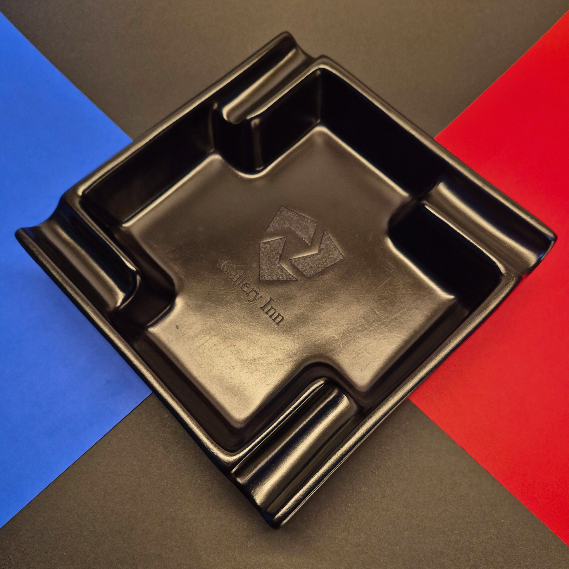 Black ashtray with 'Holiday Inn' logo on a multicolored background