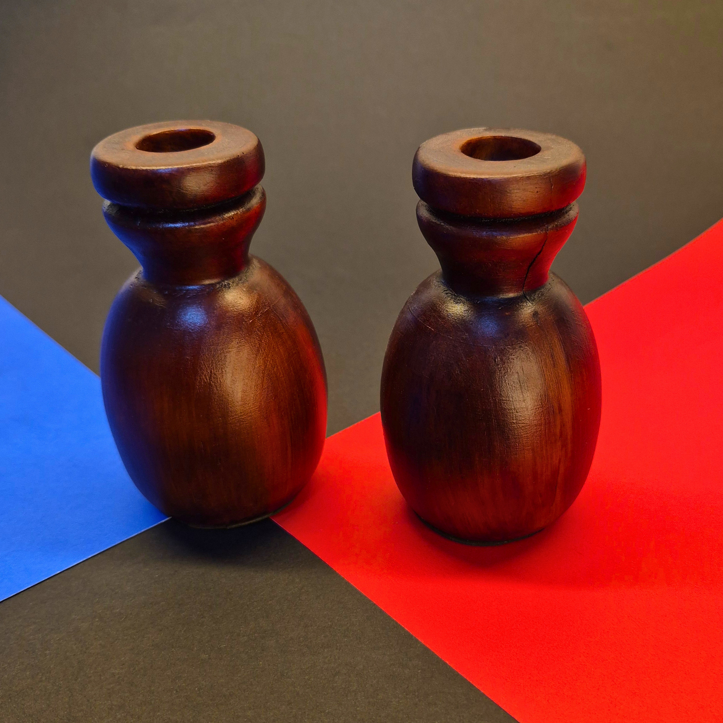 Two wooden candle holders on a colorful geometric background