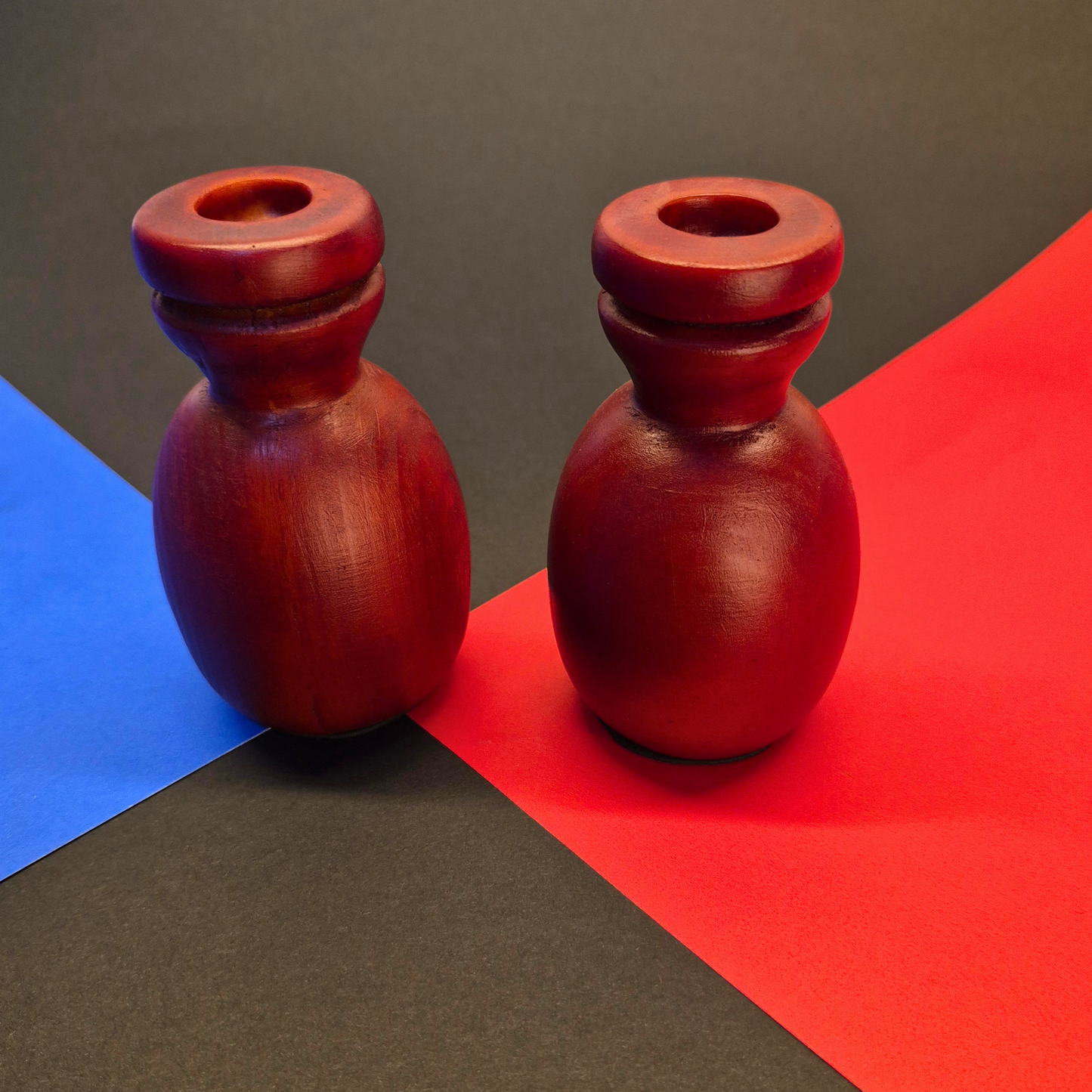 Two red wooden candle holders on a colorful geometric background