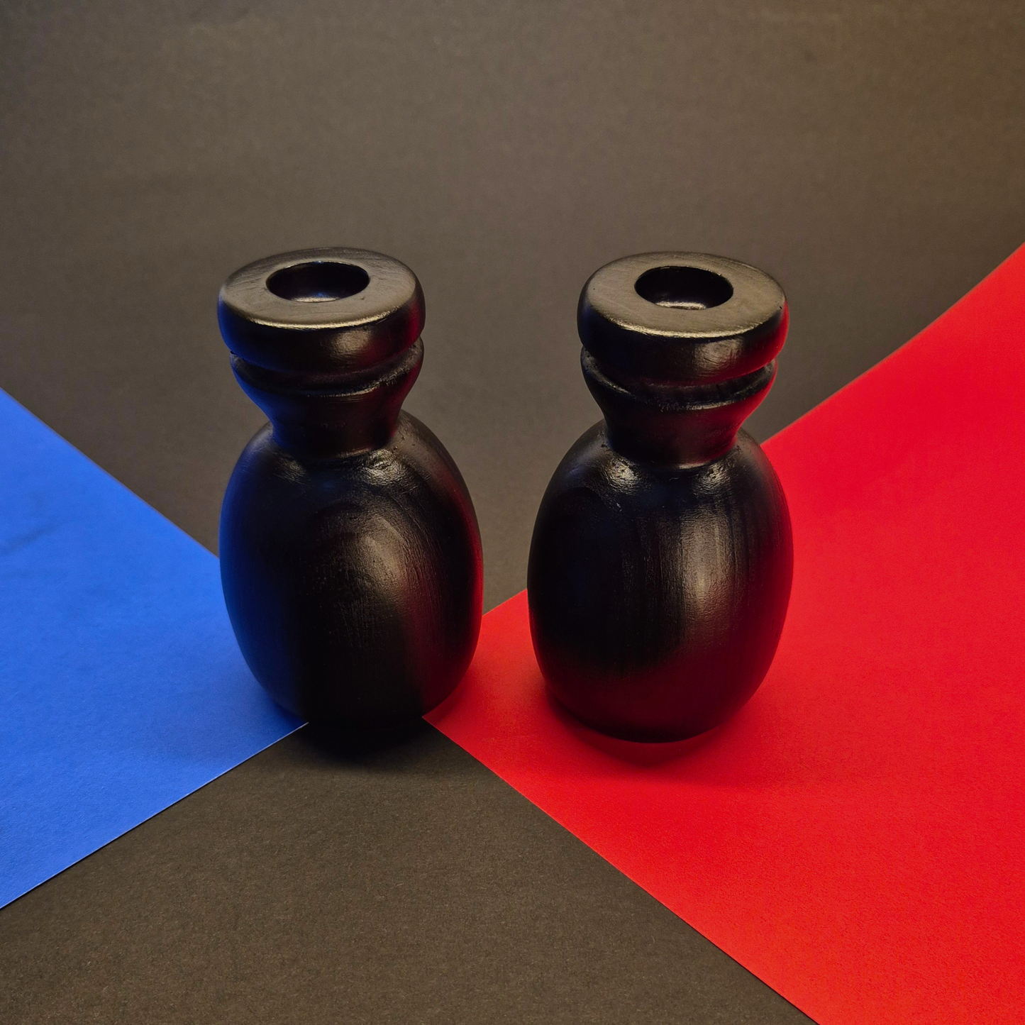 Two black ceramic vases on a red and blue geometric background