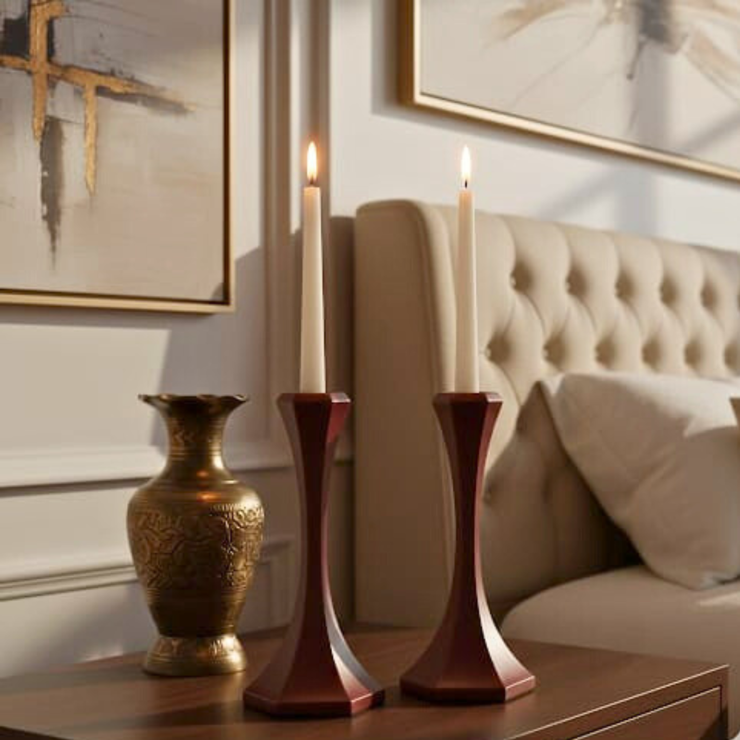 Decorative items including a gold vase and candles on a table with a couch and abstract art in the background.