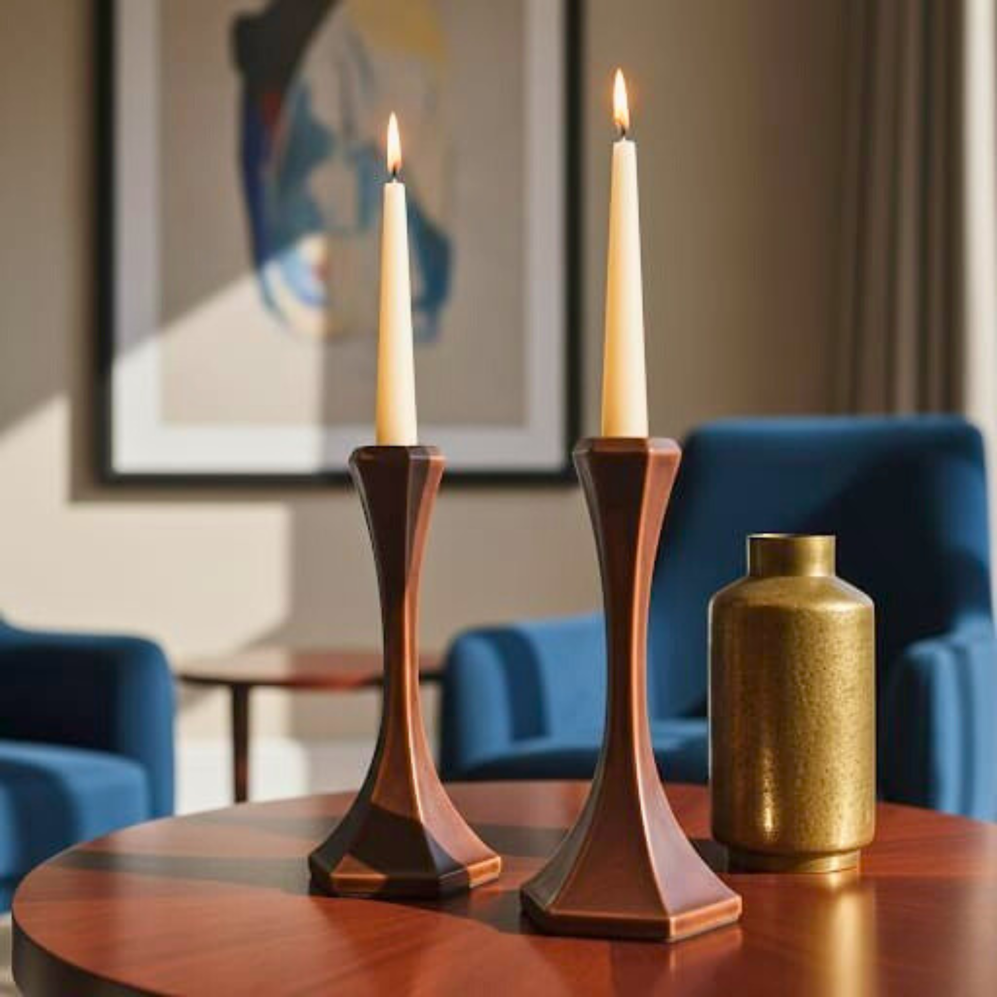 Two candlesticks with candles on a table in a living room setting.
