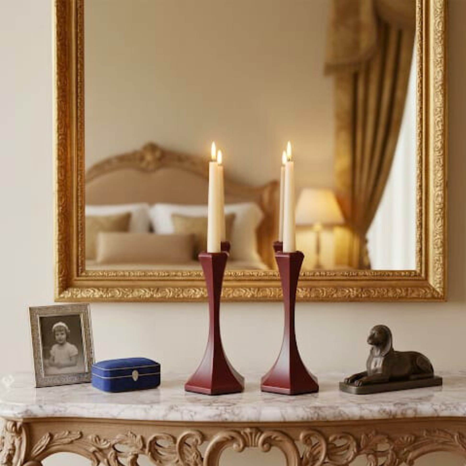 Decorative table setting with candles, mirror, and small figurines in an elegant room.