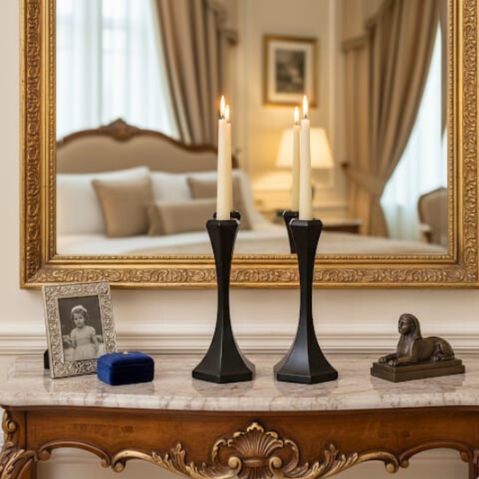 Decorative setup on a marble surface with black candle holders, a lion statue, and a framed photo in front of a large mirror.
