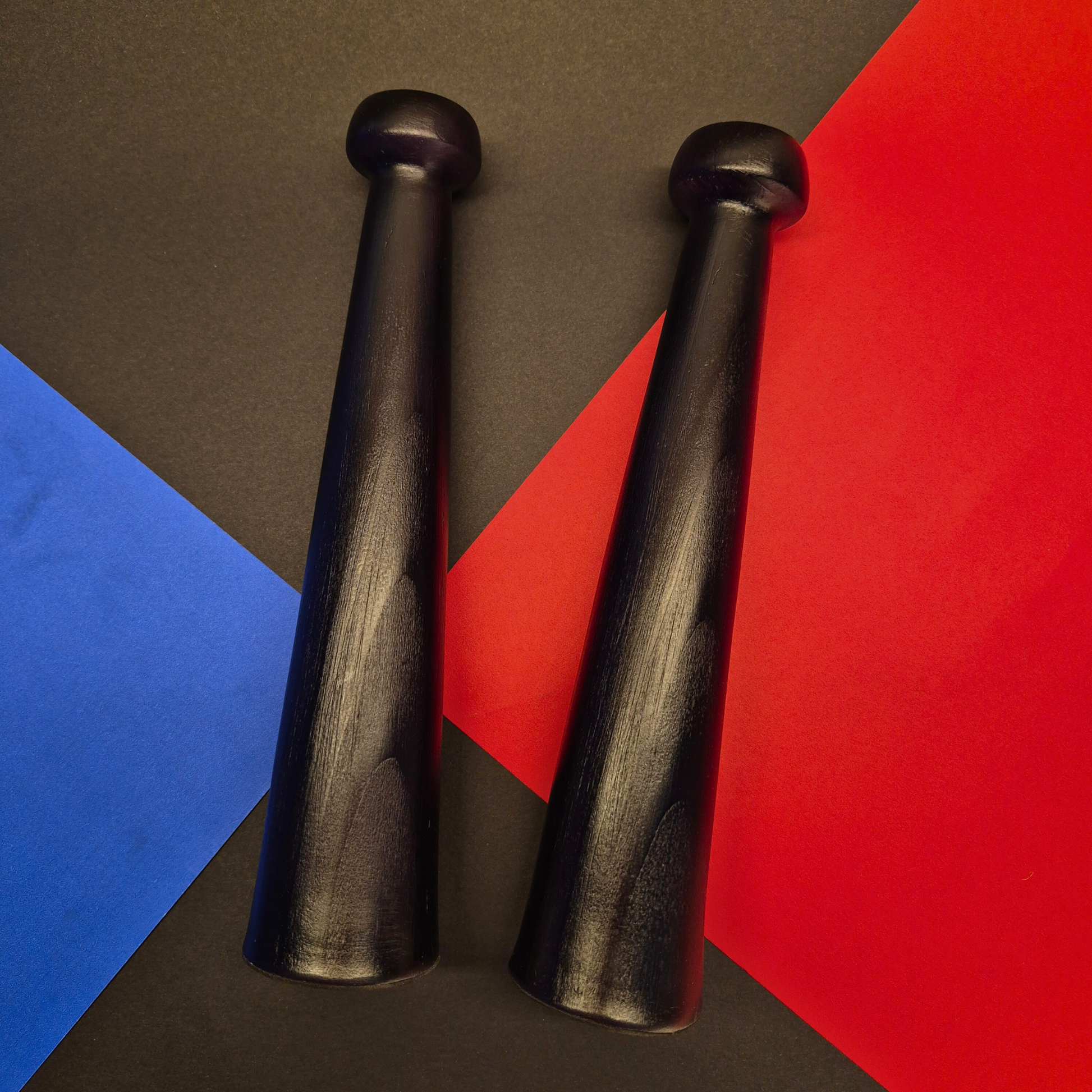 Two black wooden mallets on a colorful geometric background