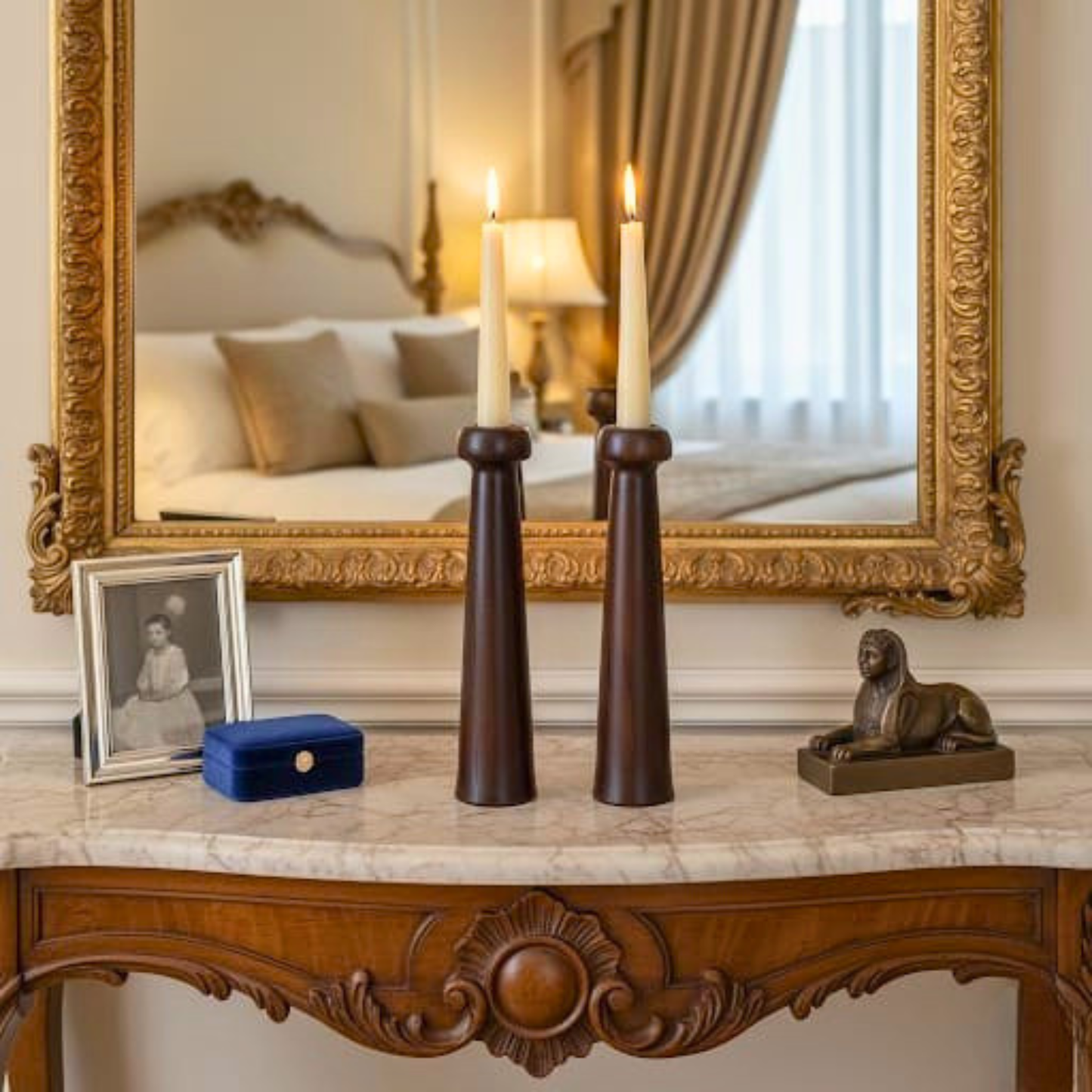 Decorative table with candles, a mirror, and small sculptures in a room.